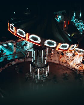 Aerial view of a brightly lit carousel at a carnival, capturing motion and light contrasts.