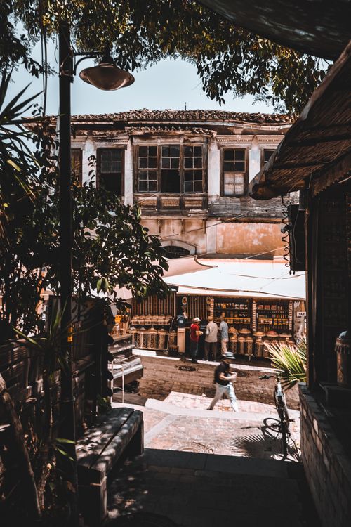 Free Historic alleyway with rustic buildings and people browsing under a sunny sky. Stock Photo