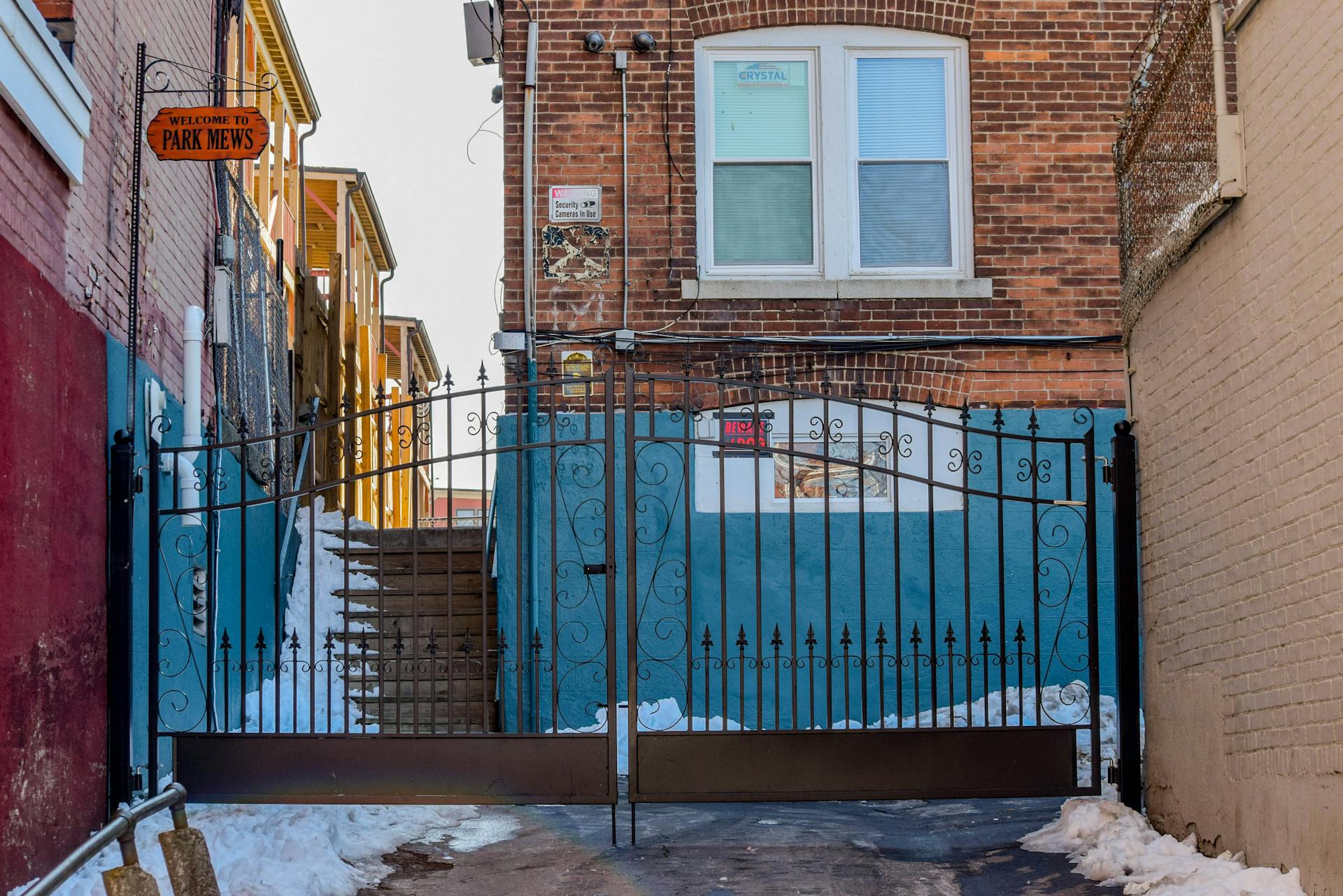 A snow-covered alleyway in Hartford, CT with a brick building and wrought iron gate.