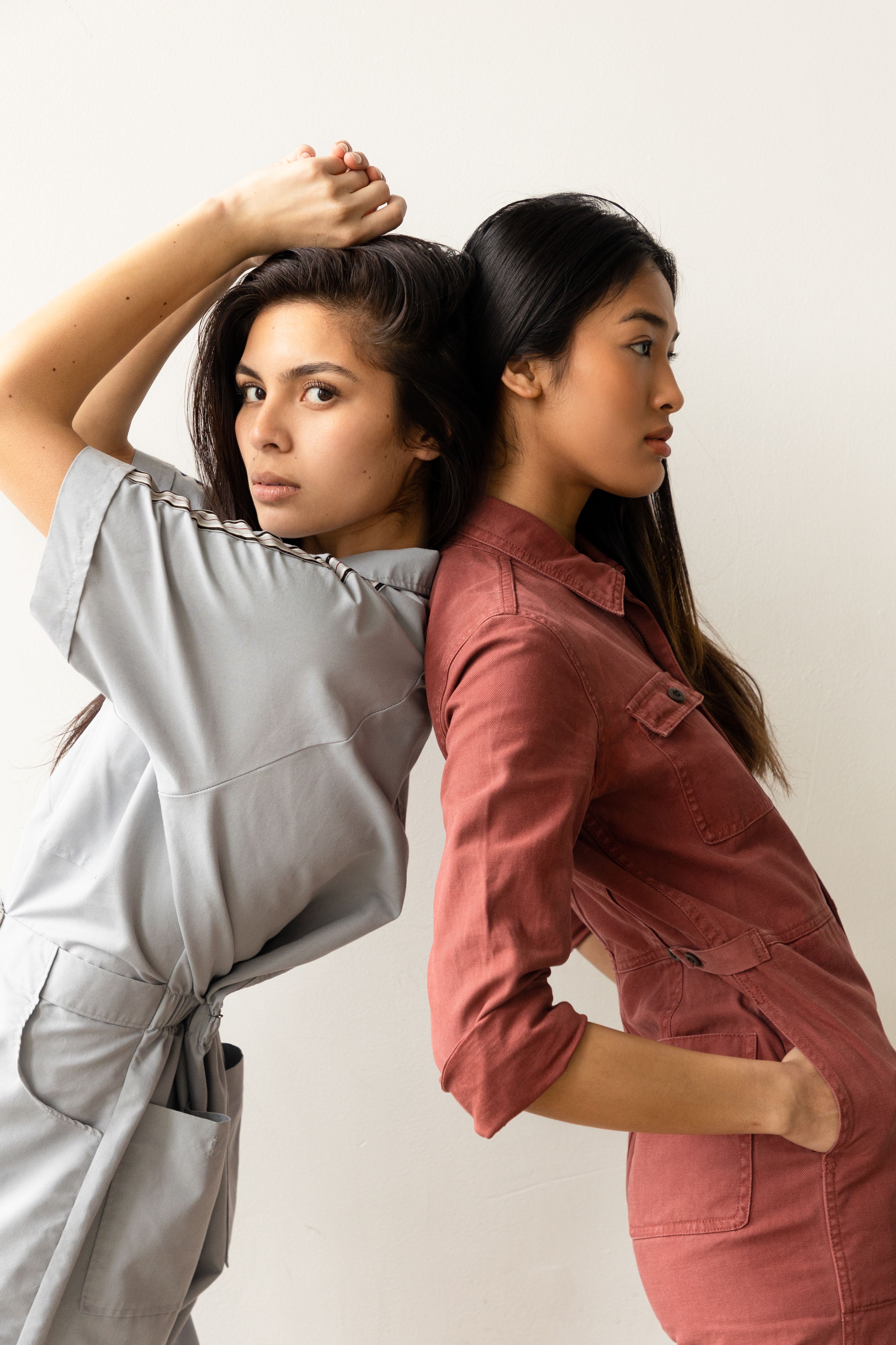 Duas mulheres posando de forma estilosa em macacões coloridos em um estúdio.
