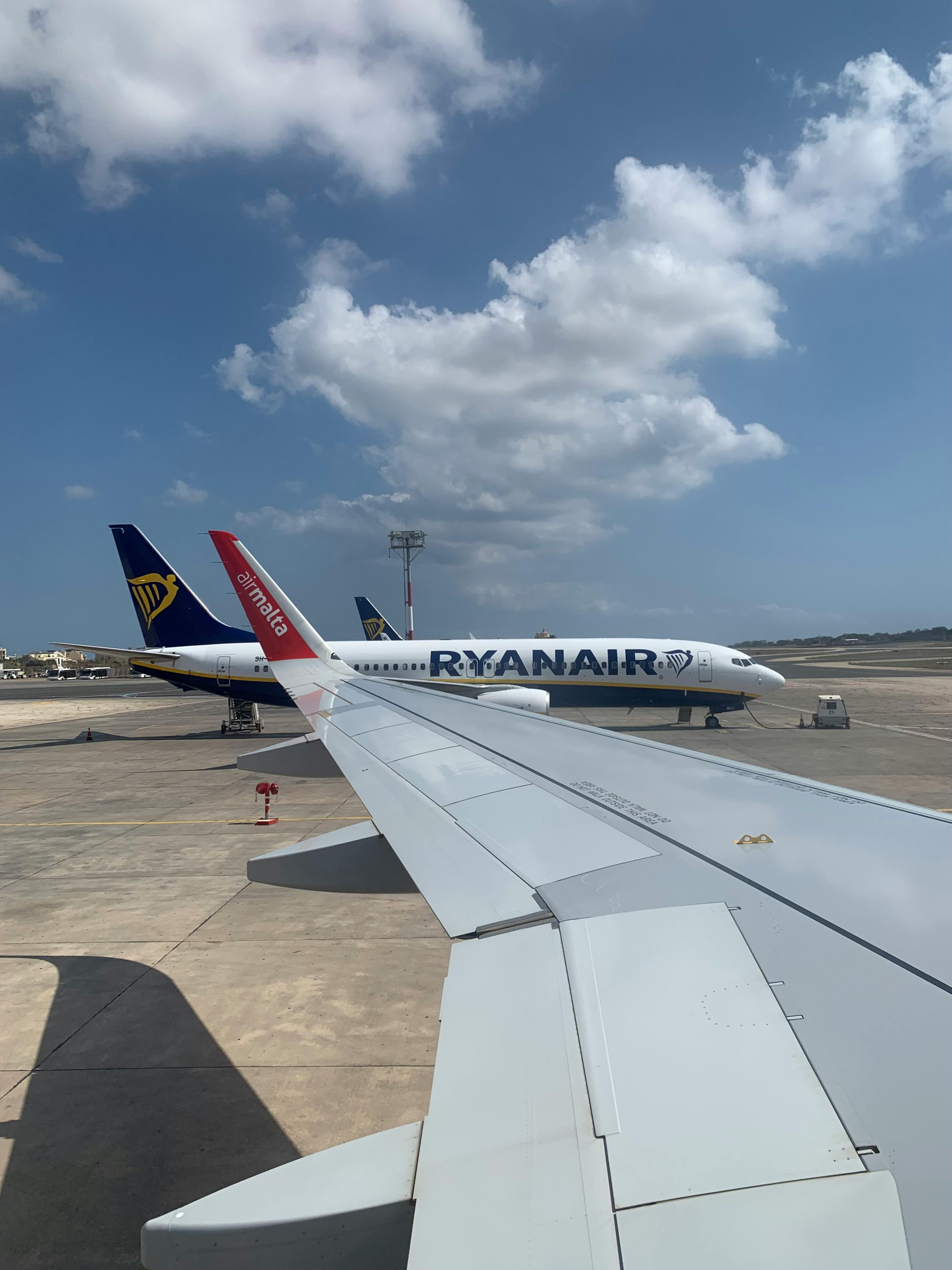 Free View of commercial airplanes from window, showcasing Ryanair aircraft on a sunny day. Stock Photo