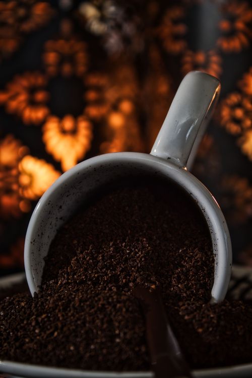 Free A close-up vertical shot of a ceramic mug filled with coffee grounds, set against an artistic backdrop. Stock Photo