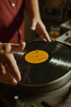 Hands adjusting a vintage vinyl record on a turntable, capturing a nostalgic music vibe.