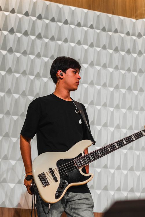 Free Portrait of a young male musician playing bass guitar indoors. Stock Photo