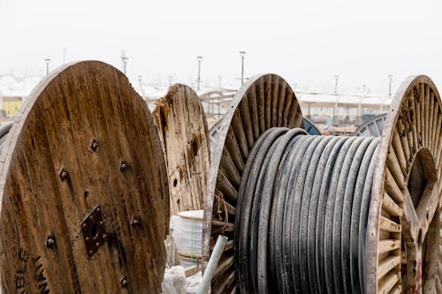 Free Close-up of large wooden reels holding industrial cables in an outdoor supply yard. Stock Photo