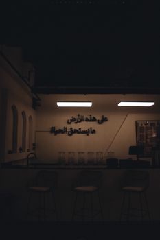 Empty coffee shop facade in Dubai with Arabic signage, minimal design, illuminated at night.