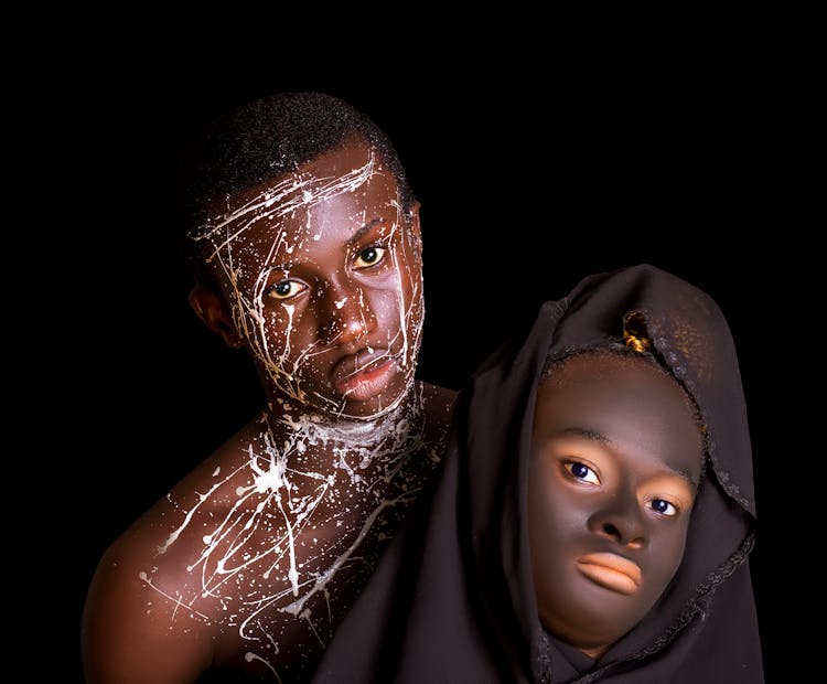 Person With White Paint And A Person Wearing A Black Headscarf