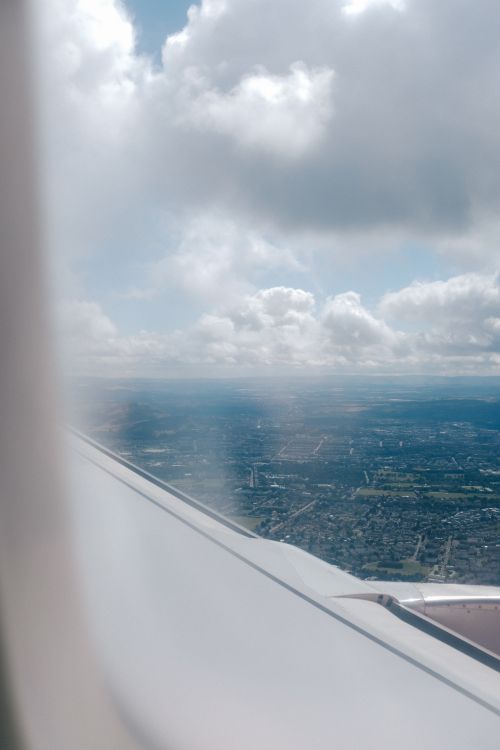Free Scenic view of land through airplane window with clouds above. Stock Photo
