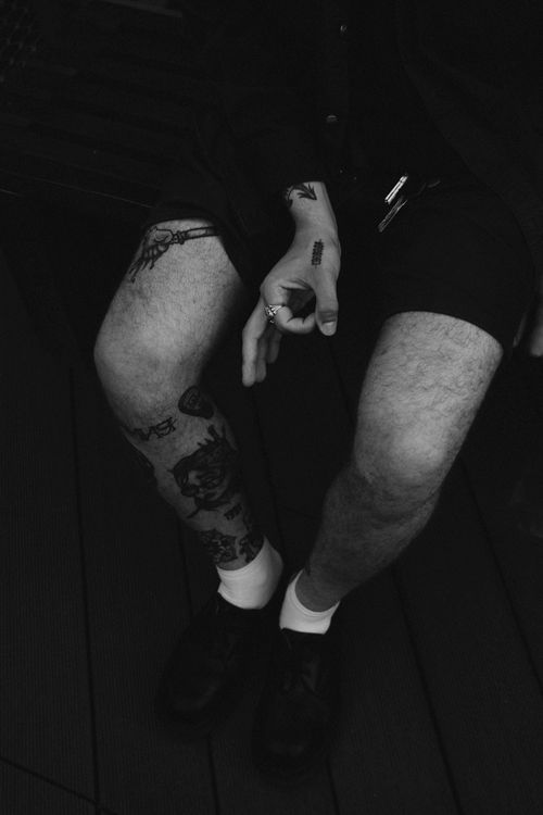 Free Black and white photo highlighting tattooed legs and hands, capturing urban style and personal expression. Stock Photo
