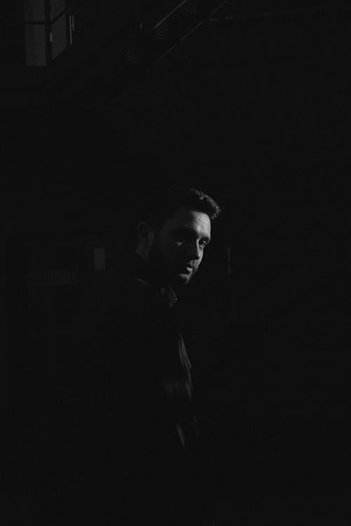 Monochrome Photo of Man in a Dark Room 