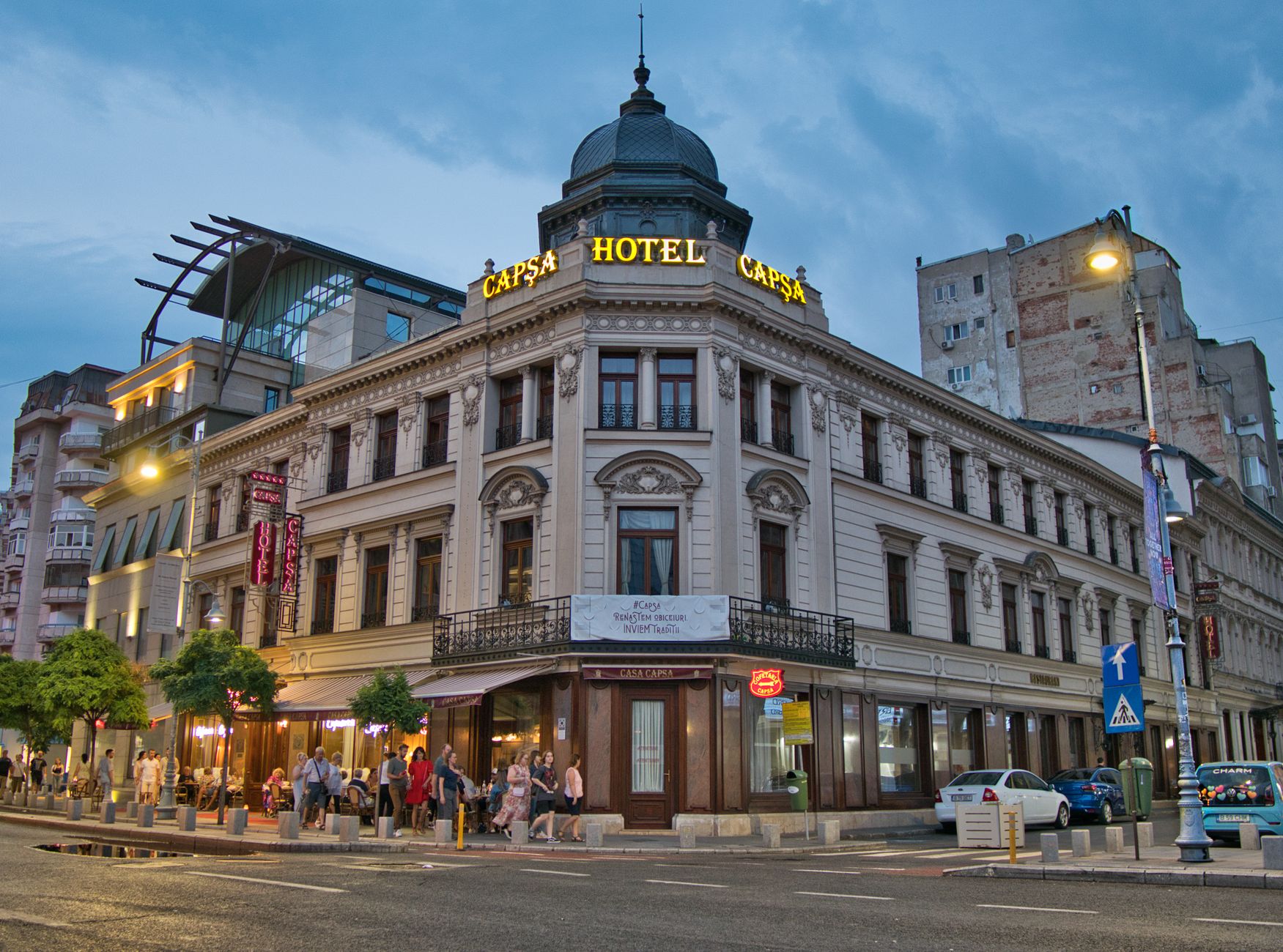 Charming view of Hotel Capsa, an architectural landmark in central Bucharest, bustling with evening life. Related image for Hospitality in Europe: How Technology Is Reshaping Strategy.