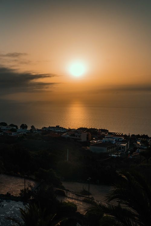 Free A stunning sunset over a coastal town with a golden ocean horizon, creating a serene and picturesque scene. Stock Photo