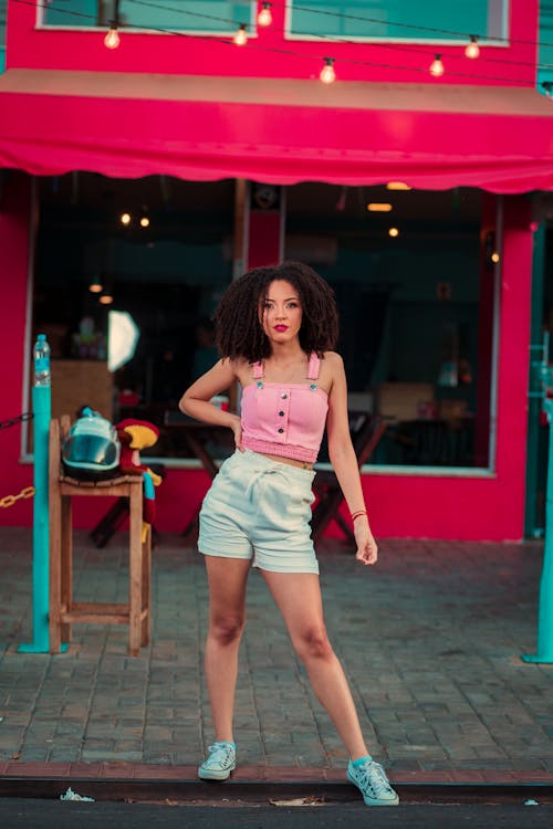 Woman in Pink Tank Top and White Shorts Posing With Hand on Waist 