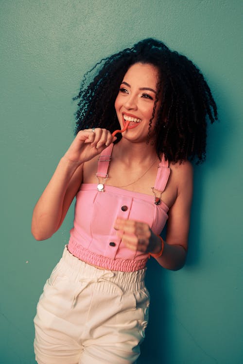 Free A Woman in Pink Tank Top Eating Candy Stock Photo