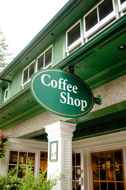 Exterior view of a quaint coffee shop with a green sign and vintage architecture.