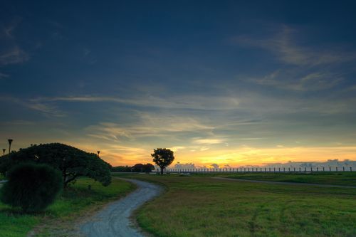 Free Tranquil park path leading through lush greenery under a vibrant sunset sky in Hualien, Taiwan. Stock Photo