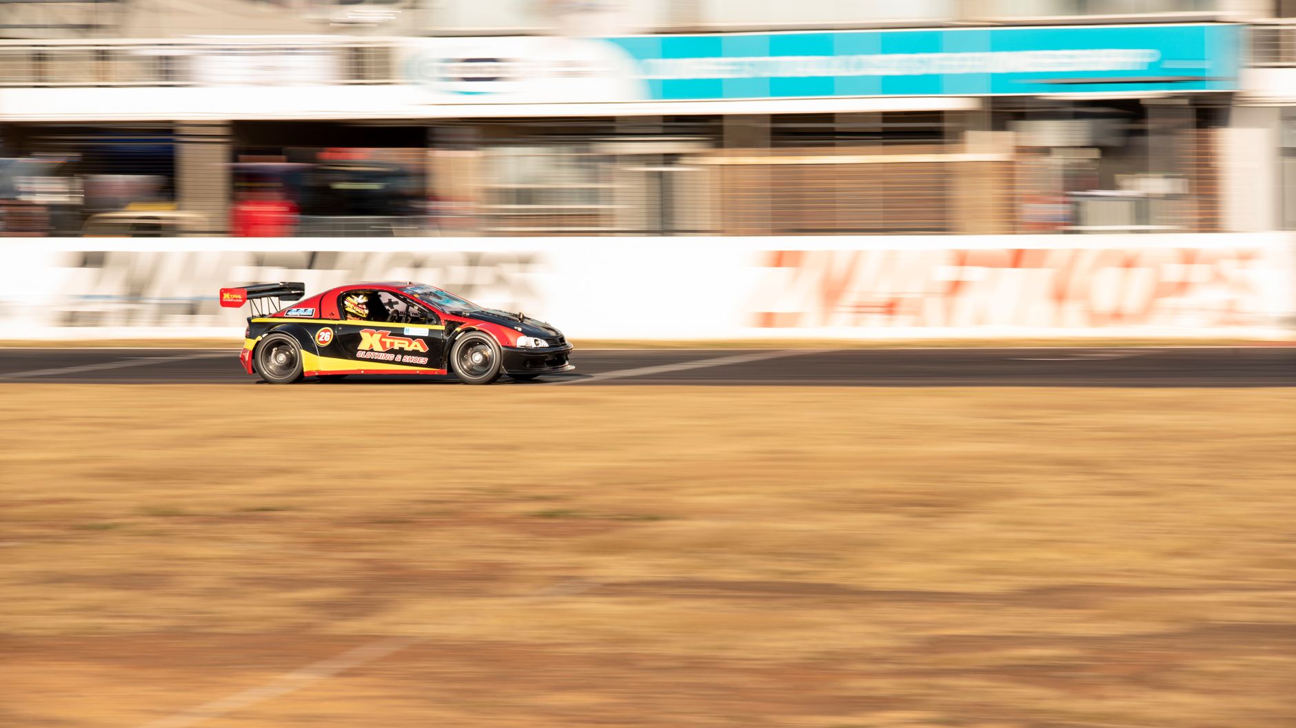 A race car speeds down an asphalt track, showcasing high-speed action and precision driving.