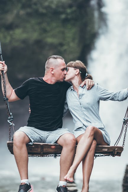 Man And Woman Sitting On Wooden Swing While Kissing