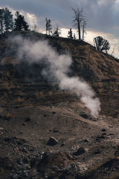 Free Dramatic hillside landscape with rising steam under a cloudy sky, captured outdoors. Stock Photo