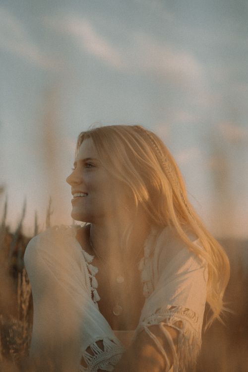 Free Portrait of a smiling woman enjoying a peaceful moment in a sunlit field. Stock Photo