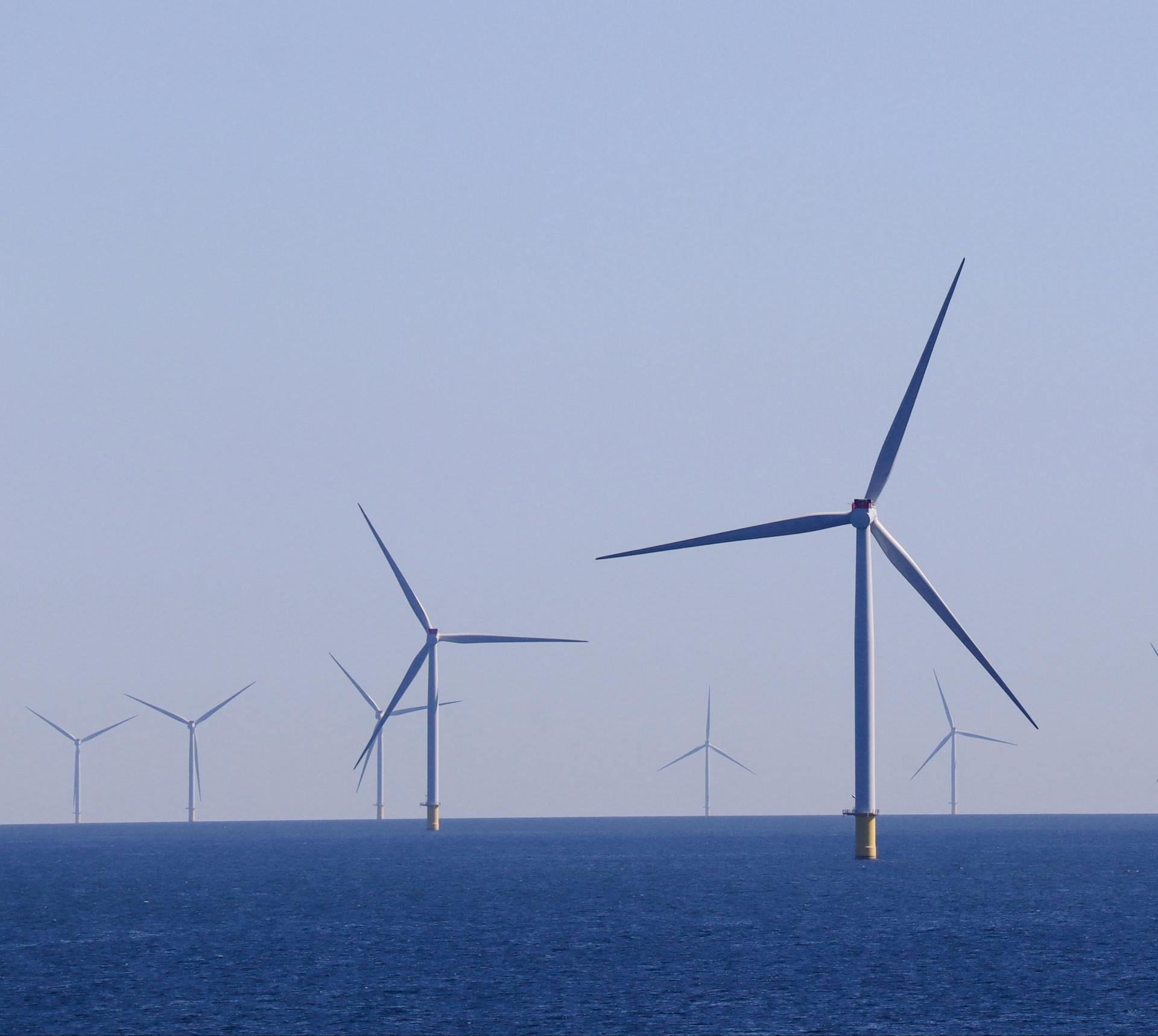 Wide view of offshore wind turbines generating renewable energy over the ocean.