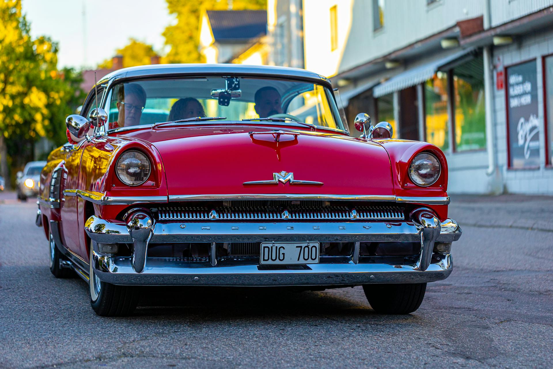 A vibrant red Mercury Montclair cruising through a city street, capturing the essence of vintage automotive design.