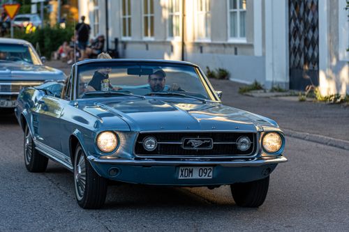 Free Vintage convertible car driving through city street with two men enjoying a sunny day. Stock Photo