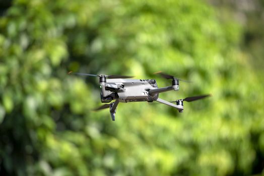 A sleek, modern drone hovering amidst a lush green backdrop, showcasing cutting-edge technology.