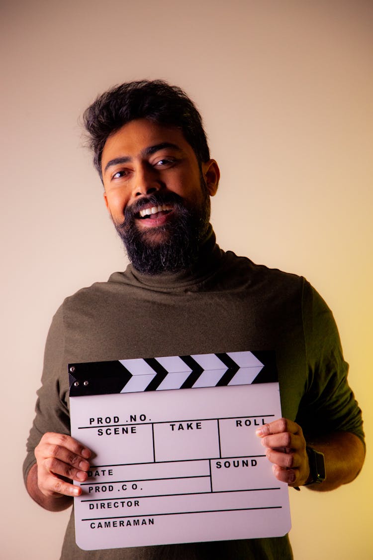 Smiling Man Holding Clapboard In Studio