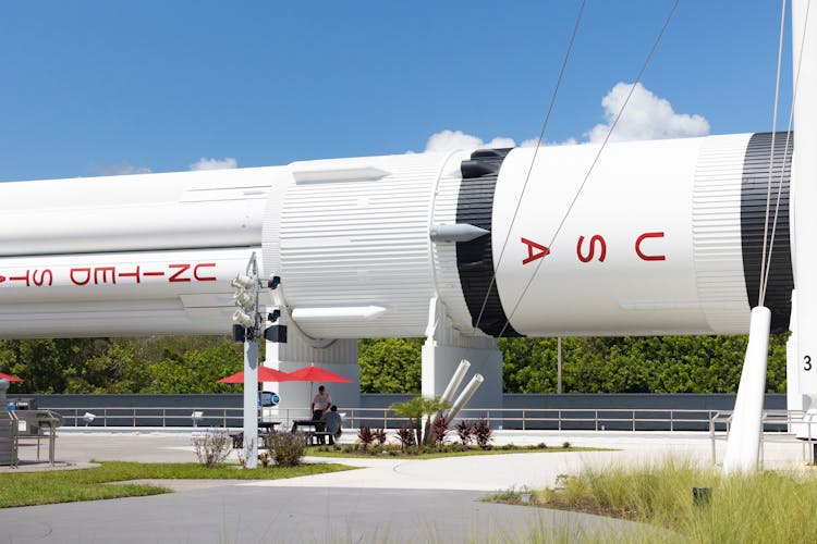 People Under Umbrellas Near Rocket Shaped Building