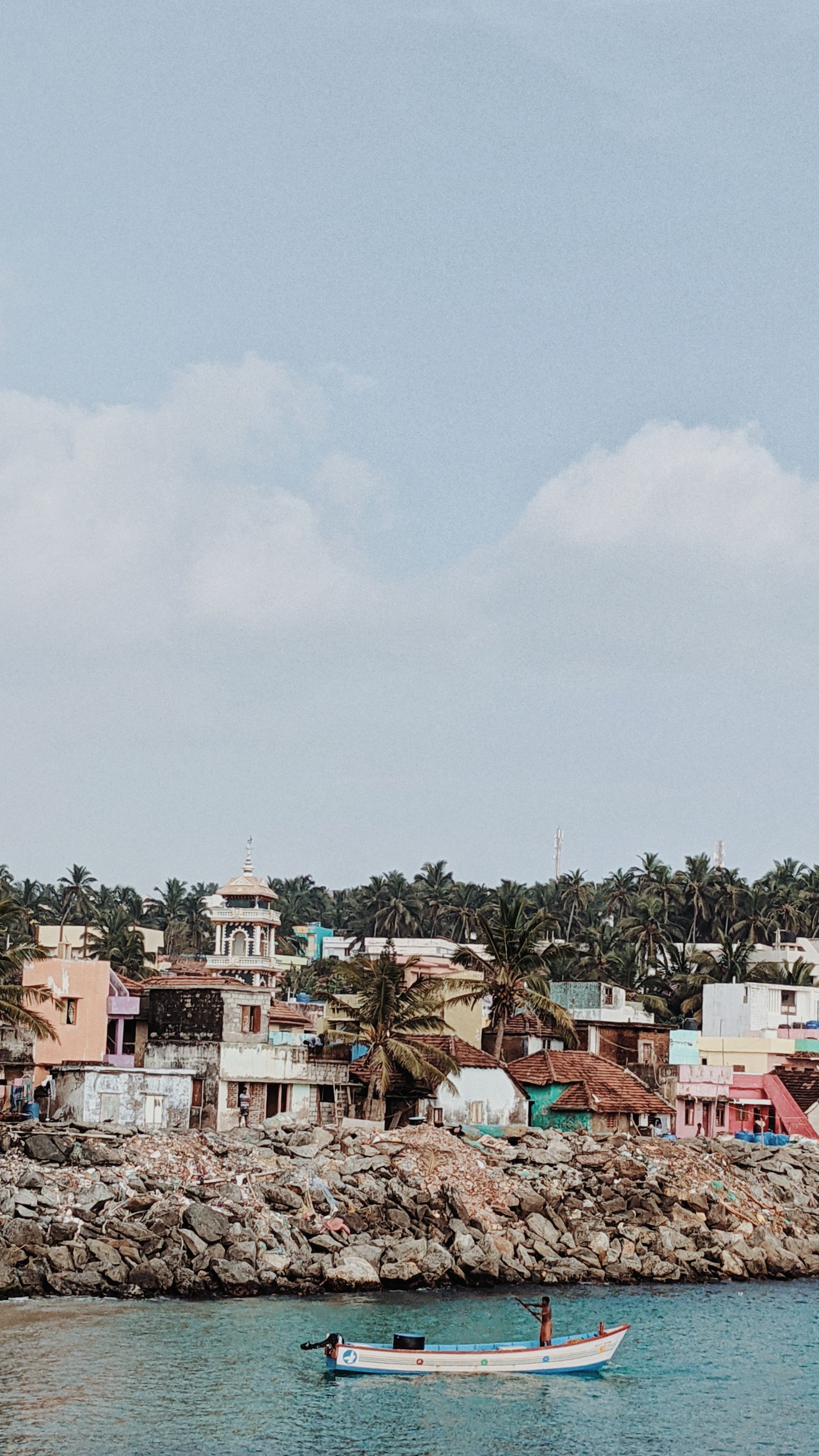 Charming coastal village with vibrant homes and a small boat in tranquil waters.