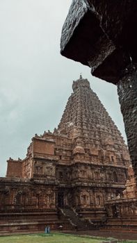 Majestic Brihadeeswara Temple tower captured from a low angle under an overcast sky, highlighting its detailed architecture.