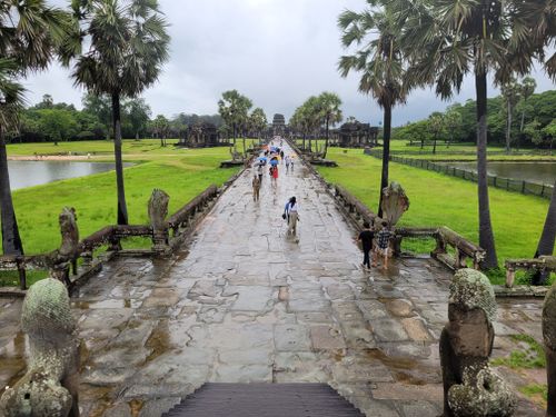 Free Tourists walking along the pathway of Angkor Wat, Siem Reap, Cambodia under a cloudy sky. Stock Photo