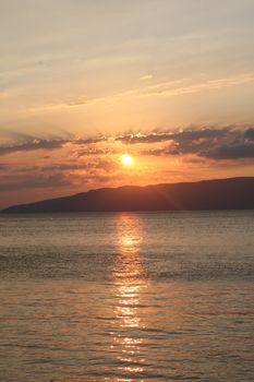 A breathtaking sunset over calm ocean waters with reflections and scenic silhouettes.
