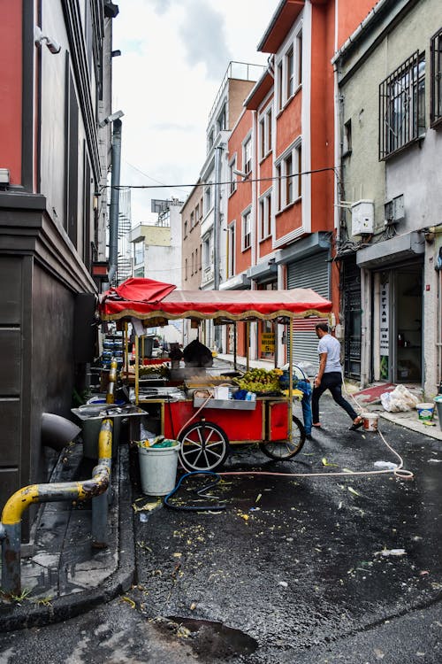 A Man Walking Near the Food Cart on the Street