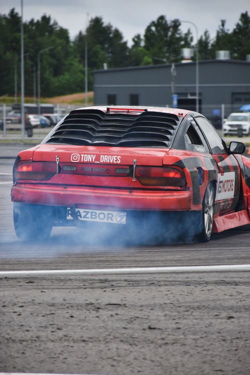 Free A red car expertly drifting with smoke on an outdoor track, showcasing vehicle control. Stock Photo