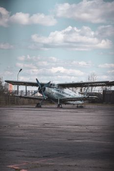 Dilapidated vintage airplane parked on deserted tarmac under cloudy sky.