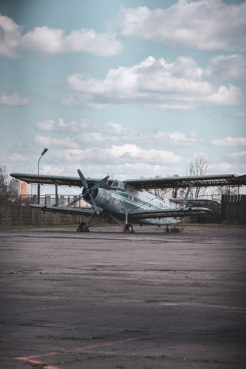 Free Dilapidated vintage airplane parked on deserted tarmac under cloudy sky. Stock Photo