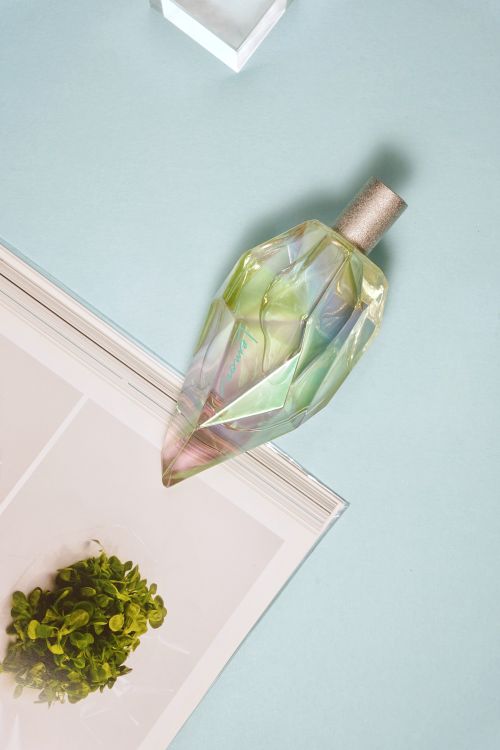 Free Stylish perfume bottle with a crystal-like design on a pastel blue background. Stock Photo