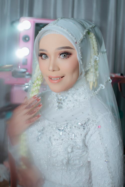 Bride Wearing a White Dress and Hijab with a Veil, Sitting and Smiling 