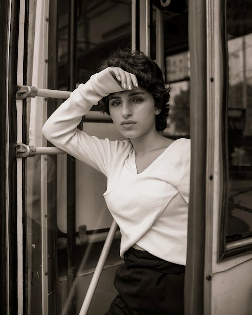 Monochrome Photo of an Attractive Woman Posing by the Bus Door