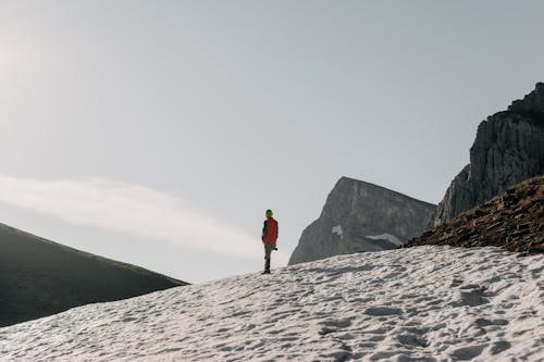 Hiker on a Snow Covered Mountain Slope Admiring the Landscape