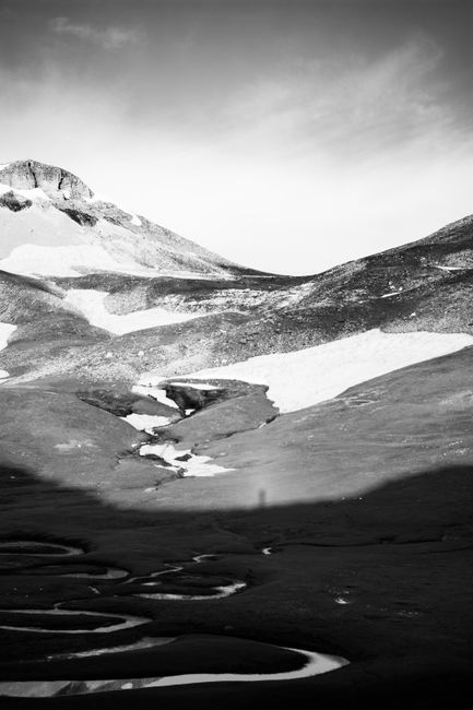 Stunning black and white photograph of mountain meanders and snow formations in a serene valley.