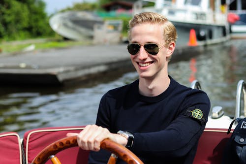 Smiling Man Driving Motorboat on Body of Water