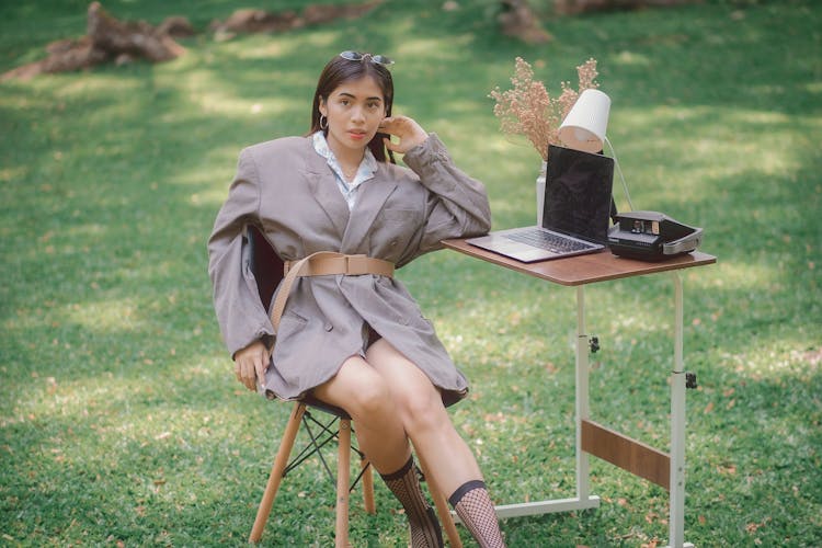 Beautiful Woman Sitting In Park With Desk And Laptop