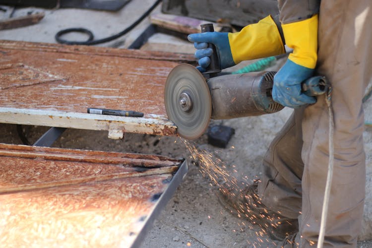 Close-up Of Man Cutting Metal With Tool