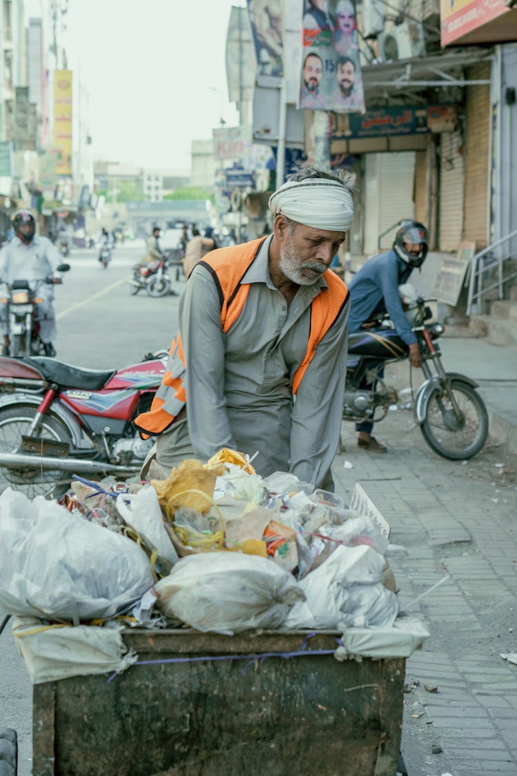 Male Worker Pulling A Garbage Bin