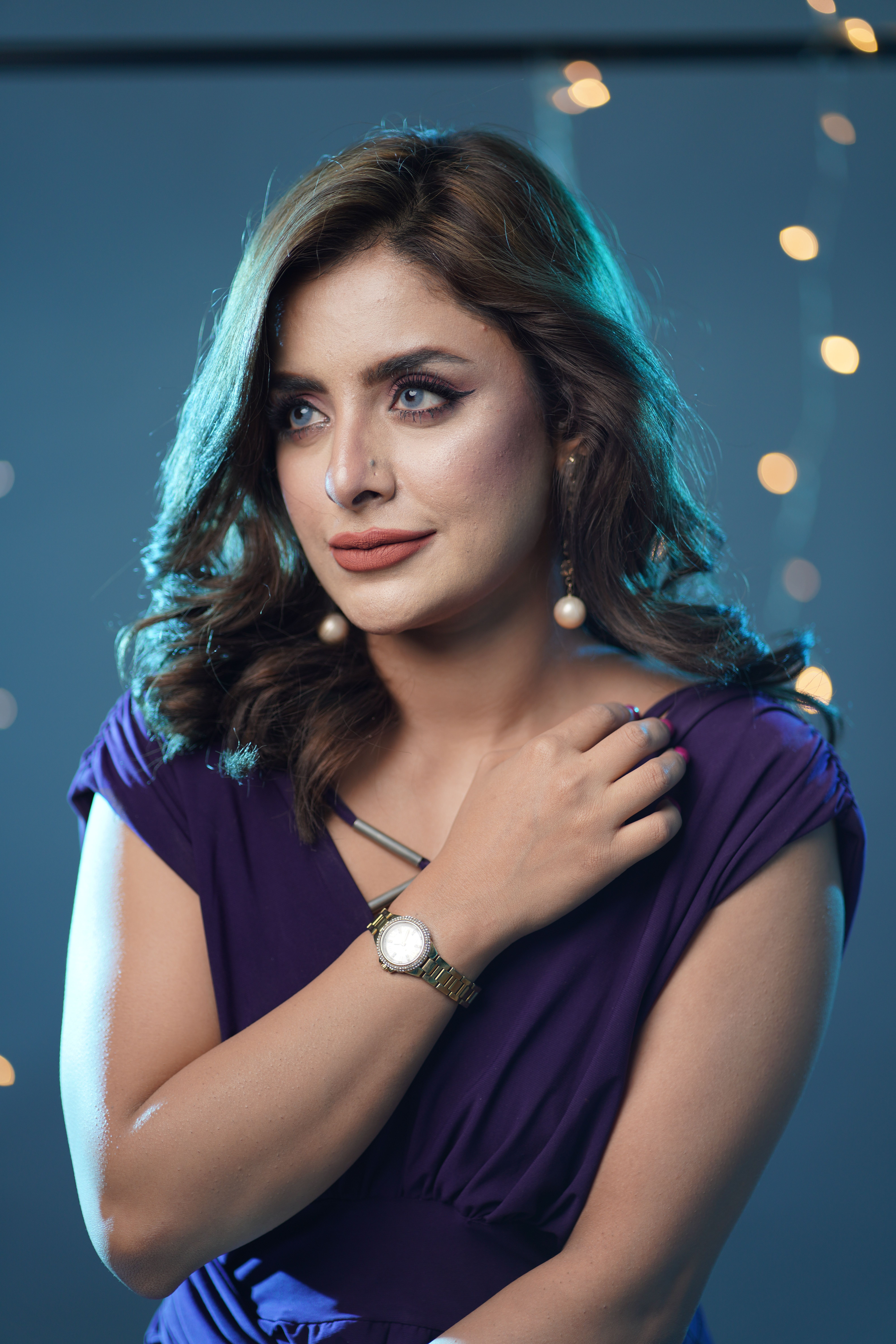 Portrait of a glamorous woman in a purple dress with bokeh lights creating a sophisticated ambiance.