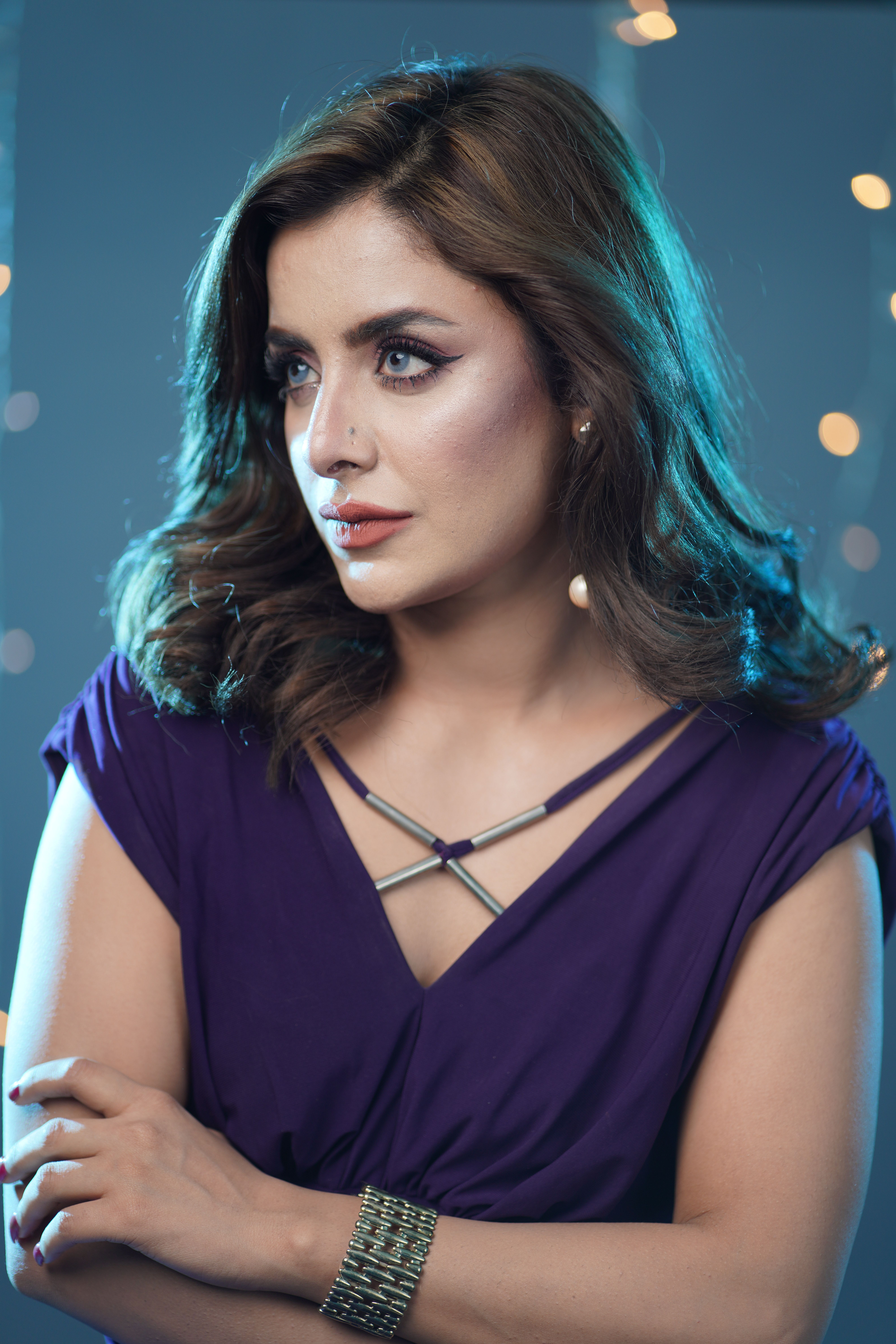 Sophisticated woman posing gracefully in a vibrant purple dress with elegant accessories.