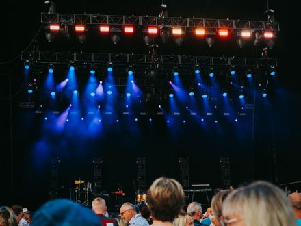 Blue stage lights over a festival crowd at night, photo by Lisa from Pexels